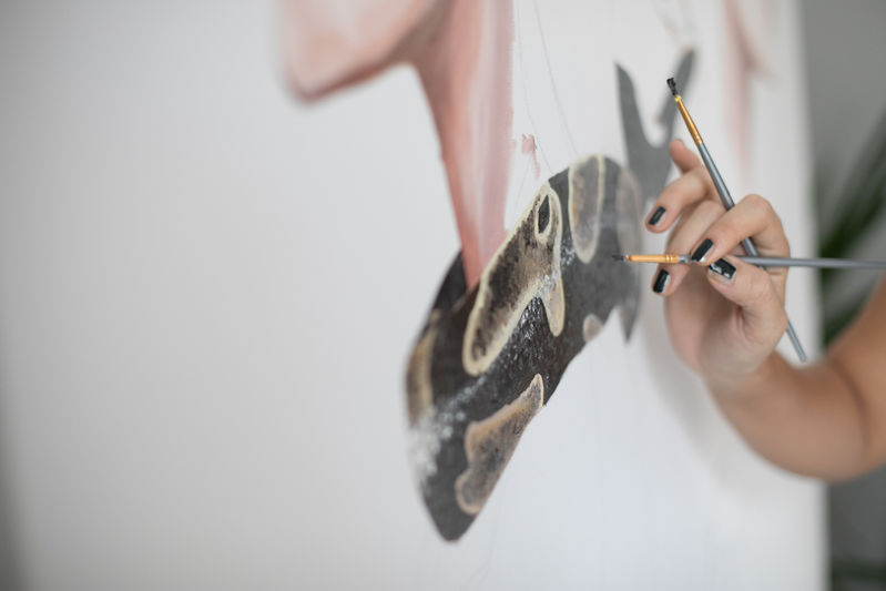 A hand at work on a painting in the artist’s studio